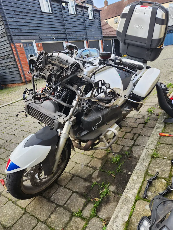 A motorcycle partly disassembled to reach its headlight bulb.